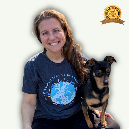 Melissa Sherman, a woman with long brown hair, is smiling and sitting with a small black and brown dog on her lap. She is wearing a dark gray shirt with a globe and text that reads, "Letting Animals Lead Us to a Better World." There is a badge in the top right corner of the image that says "Certified" and includes the logo of "Holistic Pet Health Coach."