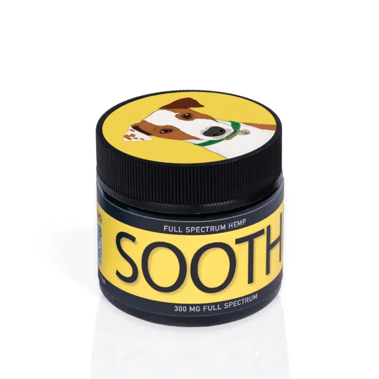 A jar of Full Spectrum Hemp SOOTHE for dogs. The jar has a yellow label with black text reading 'FULL SPECTRUM HEMP' and 'SOOTHE.' It also indicates '300 MG FULL SPECTRUM' at the bottom. The lid of the jar features an illustration of a dog with a brown and white face, wearing a green collar and a tag.